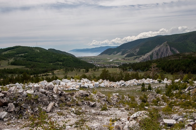 A split-screen image. On one side, a landfill shows mountains of discarded packaging materials. On the other side, a pristine forest being cleared for lumber, visually connecting packaging waste to deforestation.