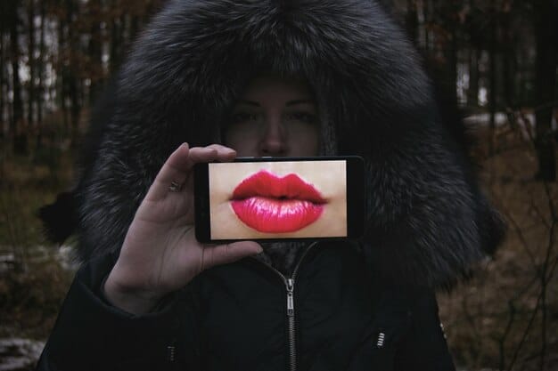 A user holding a mobile phone displaying an AR application showing different shades of lipstick overlaid on their lips.